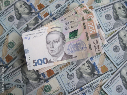 Financial background with a lot of paper banknotes of USA 100 dollars and Ukraine 500 hryvnia is great for editorial publication about money exchange. 