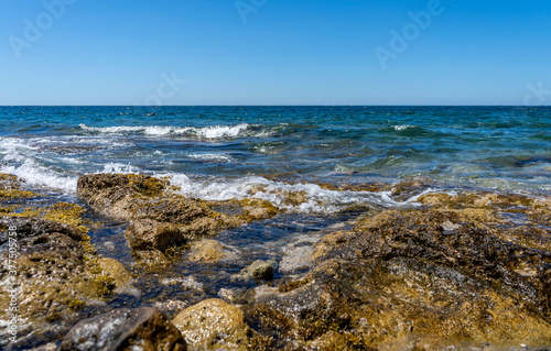 Rocky shore of Posto Rosso, Salento, Puglia, Southern Italy, in a sunny summer day, with bright colors, clear water and blue sky. 