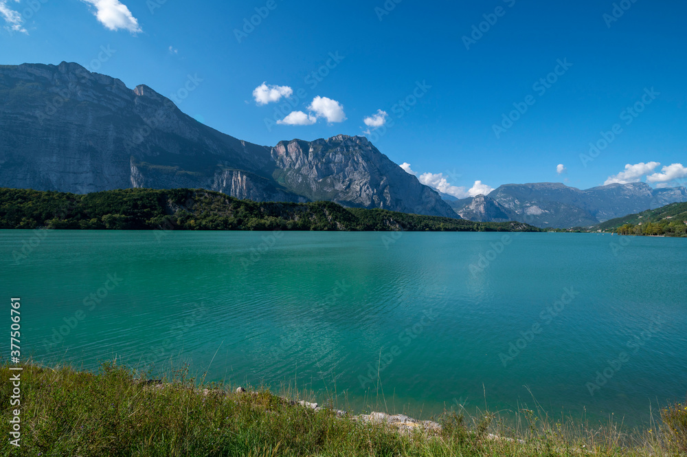 Cavedine Lake Trentino. Panorama of the turquoise blue water with mountains and vegetation on a summer day. Lago di Cavedine is a small alpine lake near, South Tyrol, Italy
