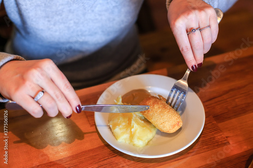 Woman uses a knife and fork for eating a cutlet