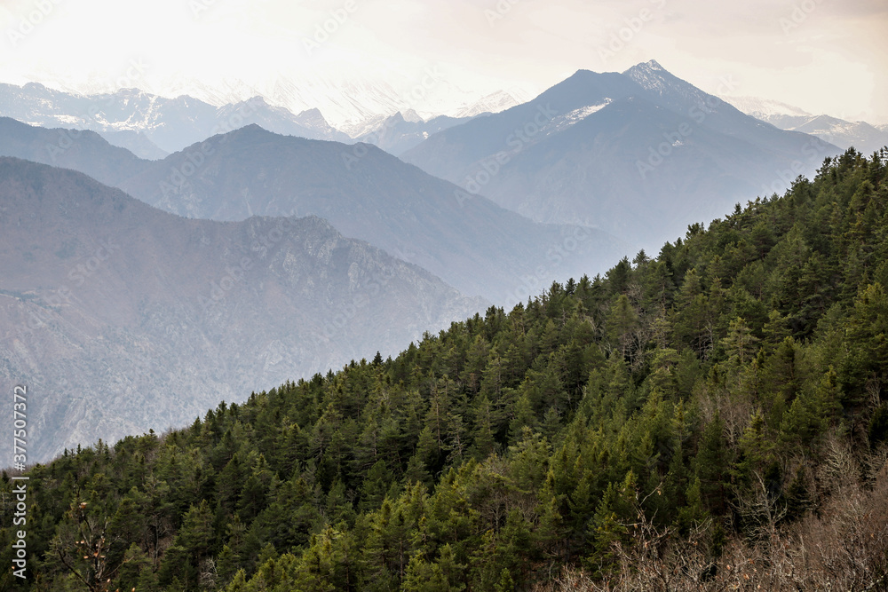 Range of mountains seen from above with clouds and forests Range of mountains seen from above with clouds and forests