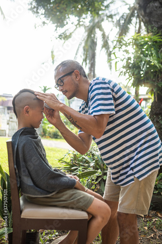 A man giving a boy a mohawk haircut in the garden during the community quarantine in the Philippines. © Jonathan