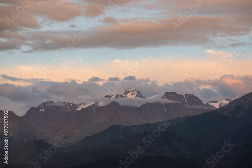 Fototapeta Naklejka Na Ścianę i Meble -  Sunset over the mountains, peaks covered with clouds, scenic sky 