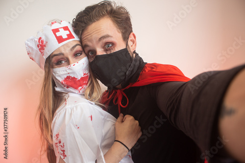 Couple taking selfie with face mask while they do funny faces for Halloween. photo