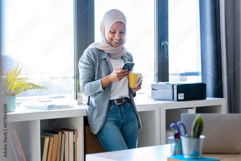 Beautiful young muslim business woman wearing hijab using her smart ...