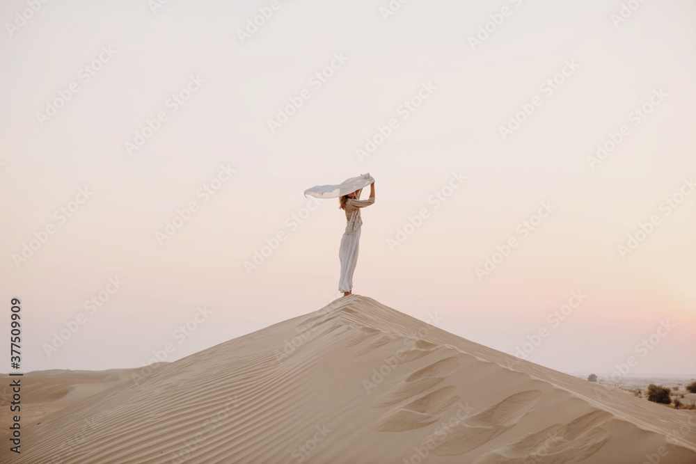 Fototapeta premium Woman holding scarf in the sand dune in desert