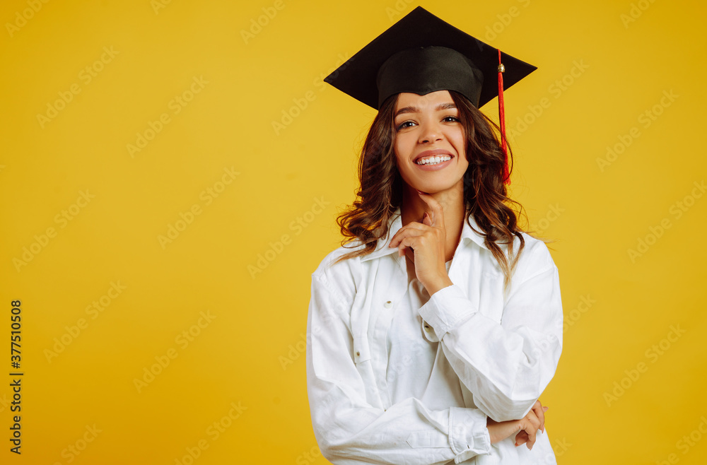 Portrait of Graduate woman in a graduation hat and in white shirt. Study, education, university, college, graduate concept on yellow banner. Portrait of Graduate woman in a graduation hat and in white shirt. Study, education, university, college, graduate concept on yellow banner.