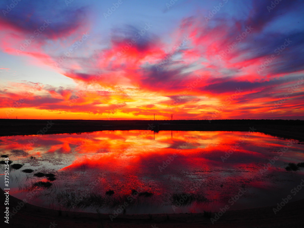 Red and orange sky reflected in a lake at sunset