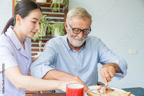Nurse assist senior man having breakfast together