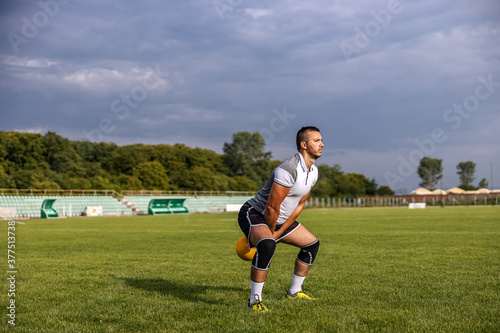 Attractive fit soccer player standing on the field and swinging kettle bell. © dusanpetkovic1
