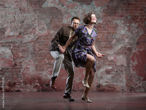 young couple dancing swing indoors in a studio against an old brick wall