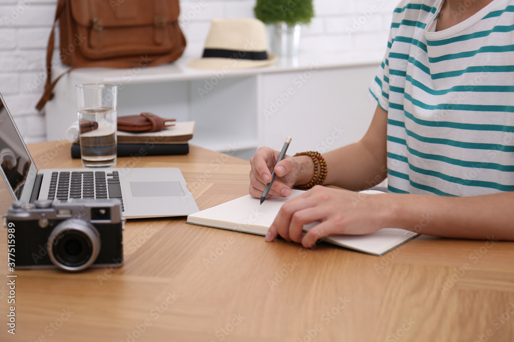 Woman with notebook planning trip at wooden table, closeup Woman with notebook planning trip at wooden table, closeup