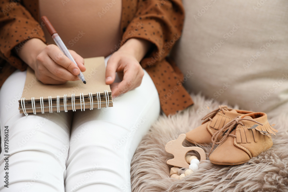 Pregnant woman writing baby names list at home, closeup Pregnant woman writing baby names list at home, closeup