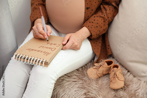 Pregnant woman writing baby names list, closeup
