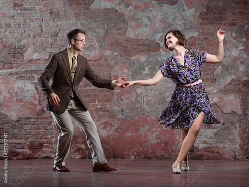 Obraz na płótnie young couple dancing swing indoors in a studio against an old brick wall