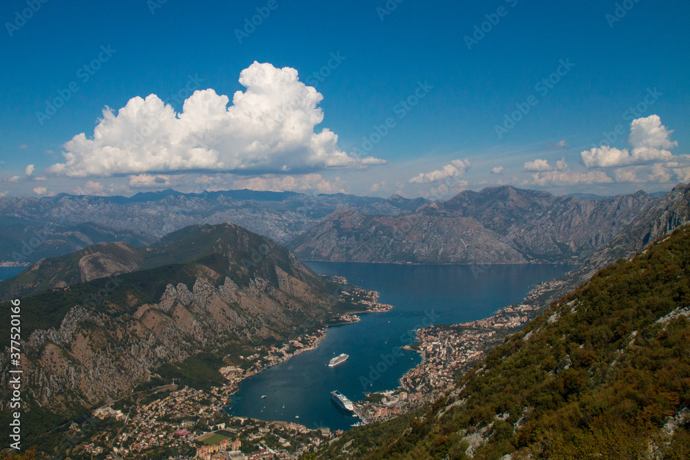 Bay of Kotor from the heights. View from Mount Lovcen to the bay. View down from the observation platform on the mountain Lovcen. Mountains and bay in Montenegro. The liner near the old town of Kotor. Bay of Kotor from the heights. View from Mount Lovcen to the bay. View down from the observation platform on the mountain Lovcen. Mountains and bay in Montenegro. The liner near the old town of Kotor.