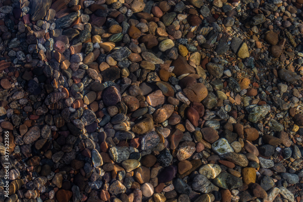 bright colored blue gold small pebbles in wave clear water sparkles in the sun, lake baikal bright colored blue gold small pebbles in wave clear water sparkles in the sun, lake baikal