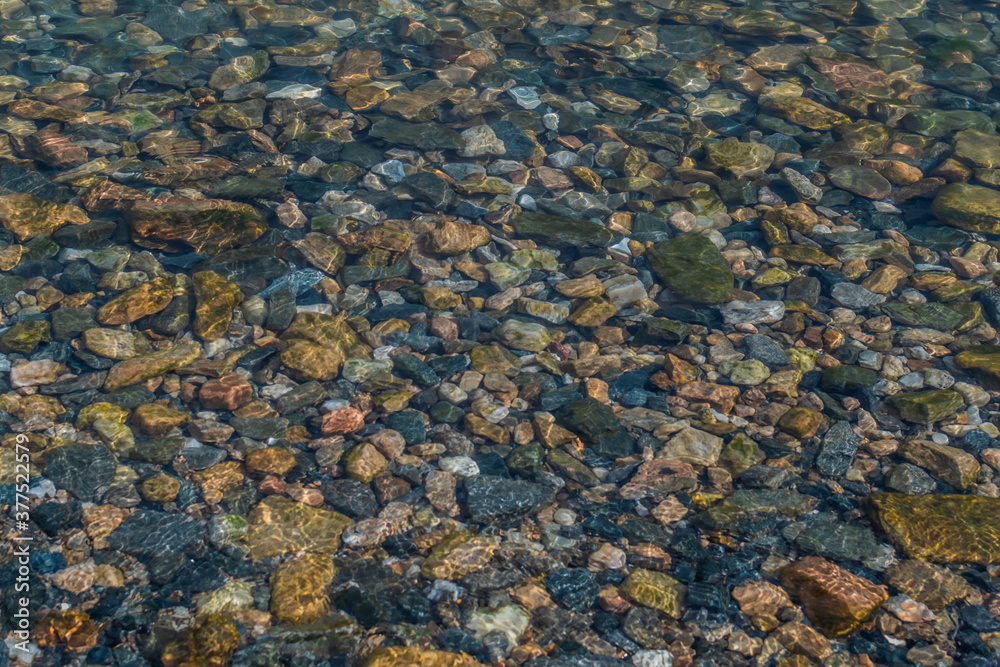 bright colored blue small pebbles in clear water sparkles in the sun, morning lake baikal bright colored blue small pebbles in clear water sparkles in the sun, morning lake baikal