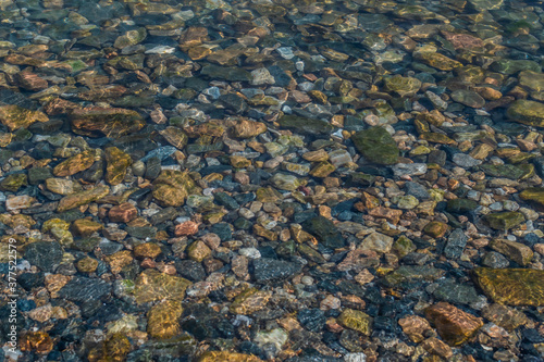 bright colored blue small pebbles in clear water sparkles in the sun, morning lake baikal