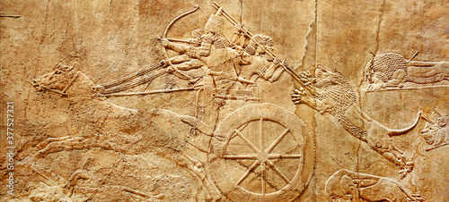 Assyrian wall relief of lion hunt, king Ashurbanipal with warriors on carving from Middle East and Mesopotamia photo