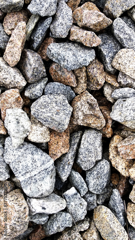 Macro photo of crushed stone and gravel on the ground. Texture background white gray stones on a black earth background.