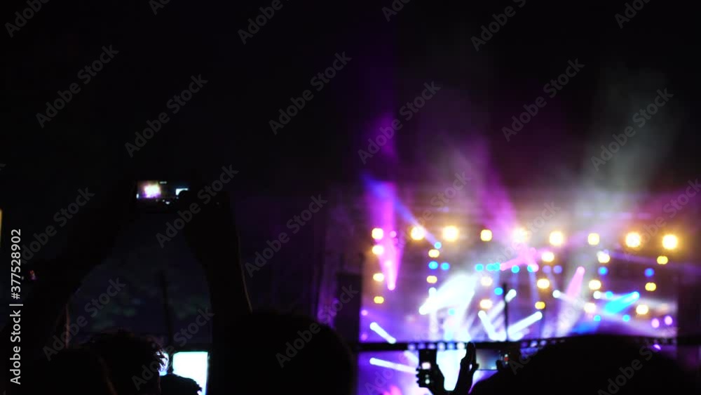 Abstract silhouette people in a crowd, hands up, dancing and holding smart phones. Out of focus stage. Handheld video Abstract silhouette people in a crowd, hands up, dancing and holding smart phones. Out of focus stage. Handheld video