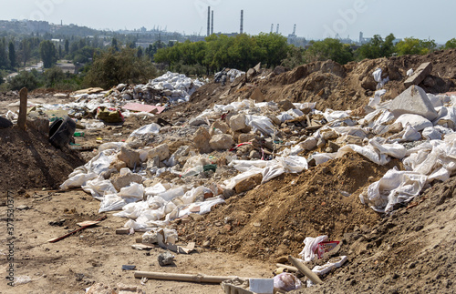 Pollution of the environment by people. Illegal garbage dump in the wasteland. A pile of household garbage in a dump in bags. A huge pile of waste extends to the garbage mountain