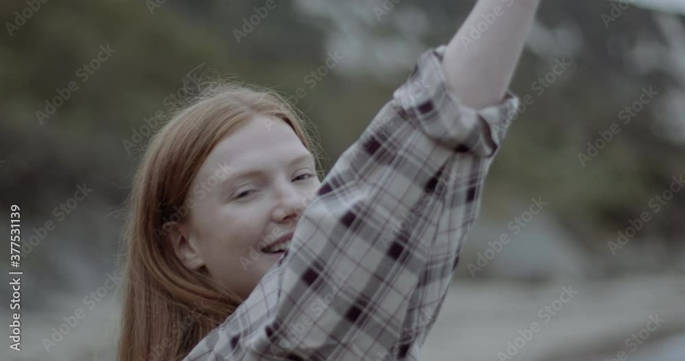Portrait of beautiful serene redhead woman dancing on beach and looking at camera Portrait of beautiful serene redhead woman dancing on beach and looking at camera