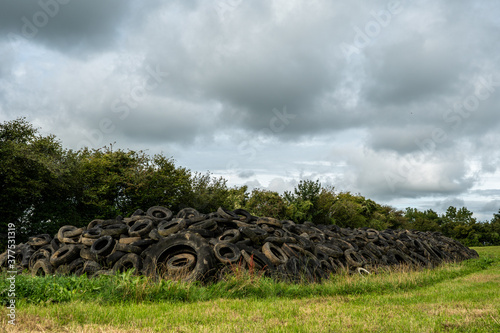 Landscape image of very large pile of tyres illegally dumped in farmland in the Somerset countryside