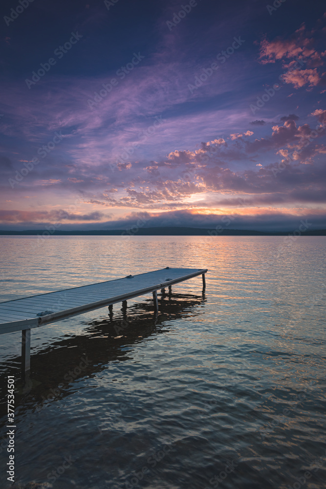 Small boat dock on Lake Bernard as morning dawns.  Vivid color paint the sky and reflect off of the lake.