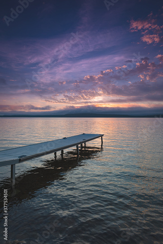 Small boat dock on Lake Bernard as morning dawns. Vivid color paint the sky and reflect off of the lake.