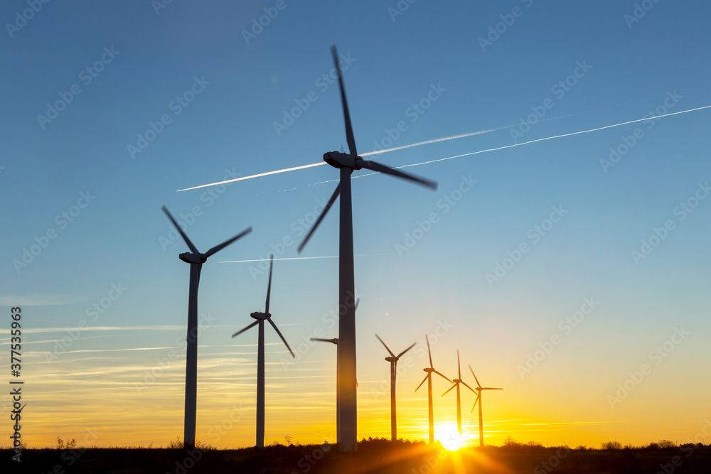 Wind Turbines at Dusk. Landscape sunset with windmills. Renewal source of electricity. Wind turbines field new technology for clean energy on mountain, sunset view with colorful twilight on sky Wind Turbines at Dusk. Landscape sunset with windmills. Renewal source of electricity. Wind turbines field new technology for clean energy on mountain, sunset view with colorful twilight on sky