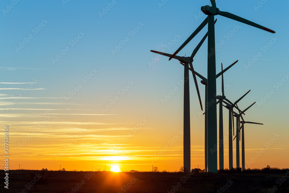Obraz premium Wind Turbines at Dusk. Landscape sunset with windmills. Renewal source of electricity. Wind turbines field new technology for clean energy on mountain, sunset view with colorful twilight on sky