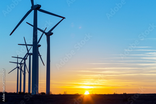 Wind Turbines at Dusk. Landscape sunset with windmills. Renewal source of electricity. Wind turbines field new technology for clean energy on mountain, sunset view with colorful twilight on sky