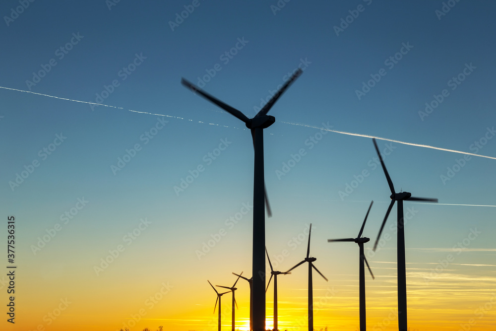 Fototapeta premium Wind Turbines at Dusk. Landscape sunset with windmills. Renewal source of electricity. Wind turbines field new technology for clean energy on mountain, sunset view with colorful twilight on sky