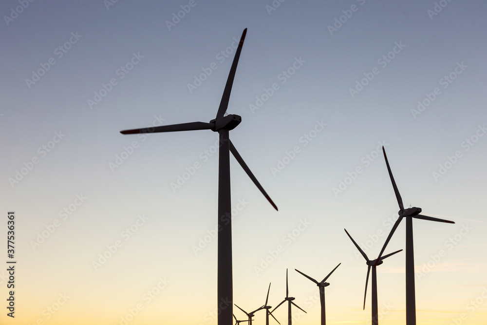 Fototapeta premium Wind Turbines at Dusk. Landscape sunset with windmills. Renewal source of electricity. Wind turbines field new technology for clean energy on mountain, sunset view with colorful twilight on sky