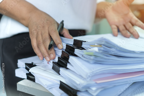 Stacks of lot documents report papers with clips waiting be managed by office workers arranging on desk in busy office. Concept of workload in business finacial paperwork information or investigate photo