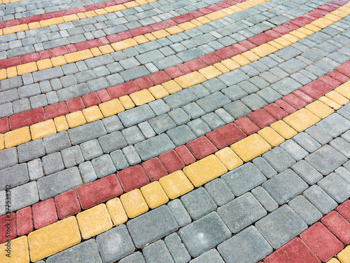 Close-up paving slabs by mosaic. Road paving, construction. Tessellated sidewalk tile. Colored concrete paving slab.