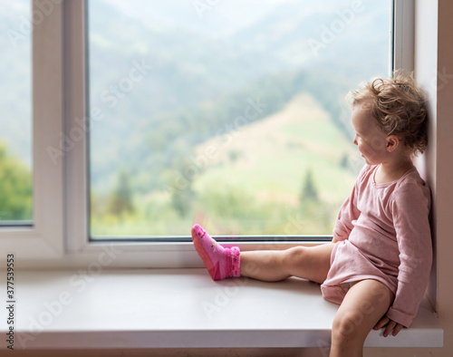 A lonely child looks out the window.