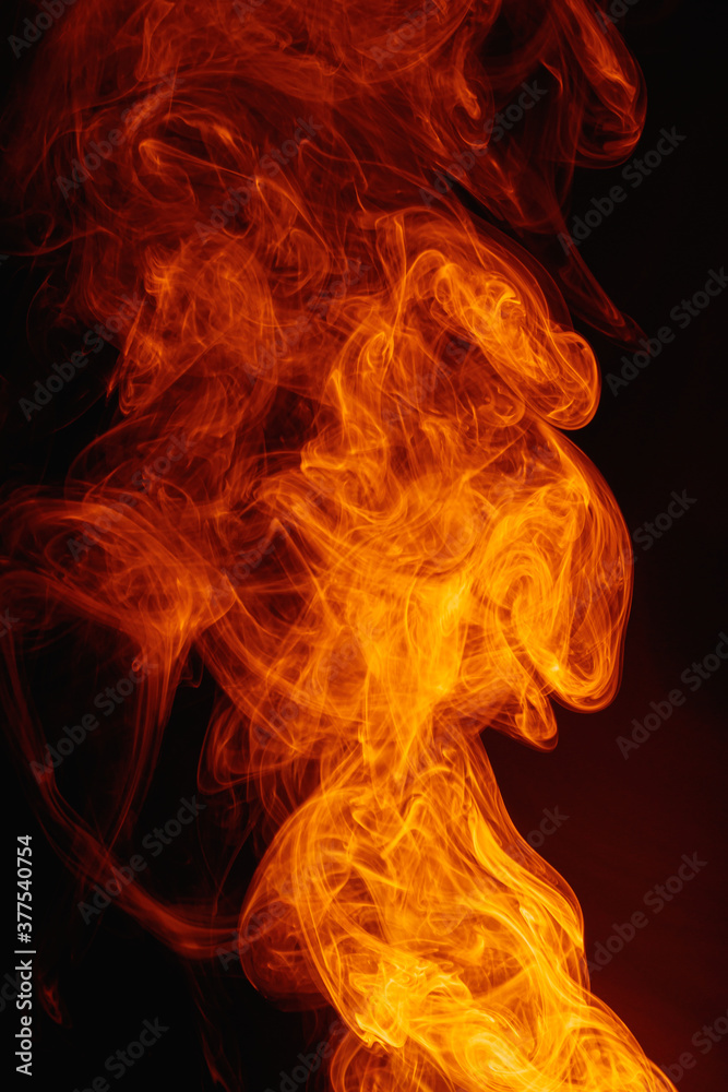 Orange smoke on a dark background. Intricate swirls of colored smoke. An abstract imitation of night flames. Orange smoke on a dark background. Intricate swirls of colored smoke. An abstract imitation of night flames.