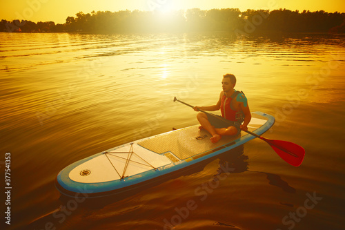 Silhouette of man paddling on paddle board at sunset. Water sport near the beach on sunset © Myshkovskyi