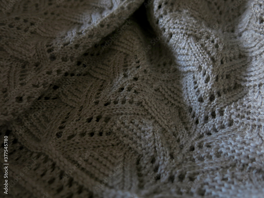 Textured beige knitted sweater with holes in the daylight. Shadow                              
