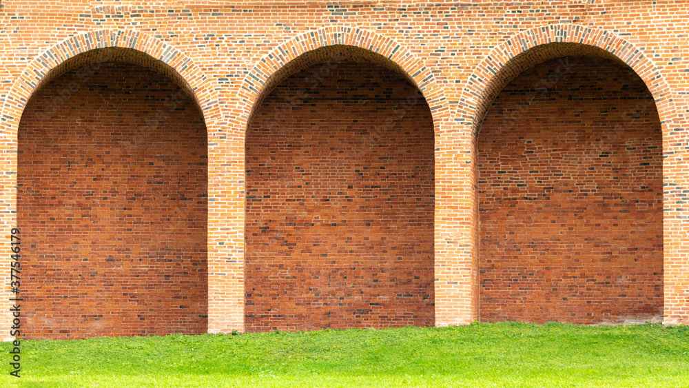 red brick wall with semicircular arches inside