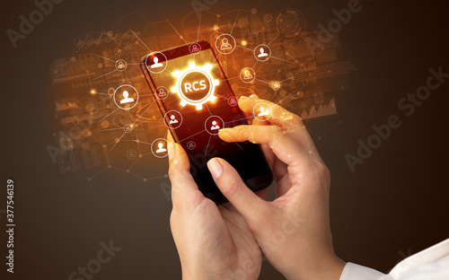 Obraz na płótnie Female hand holding smartphone with RCS abbreviation, modern technology concept w salonie