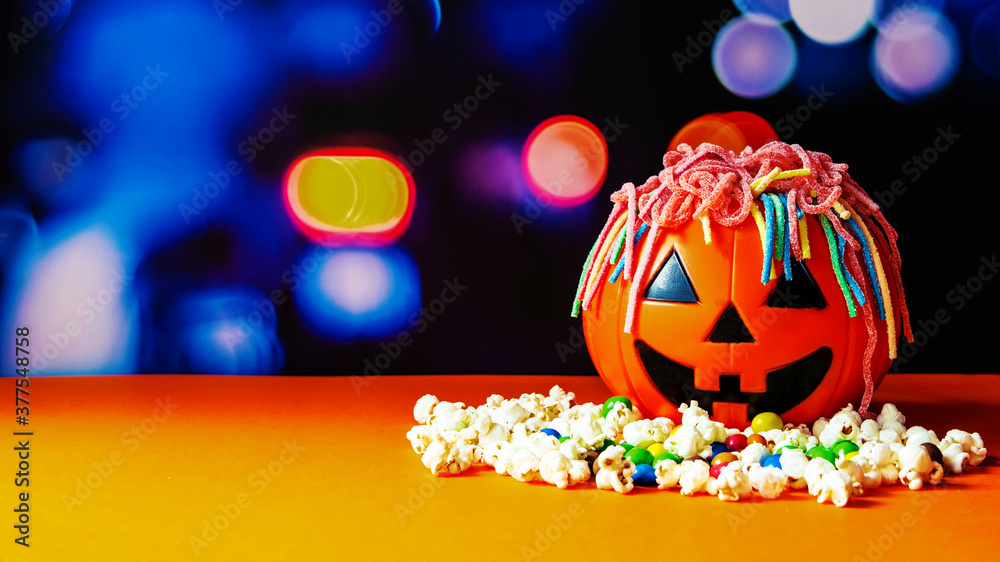 Fototapeta premium Calabaza de halloween llena gominolas formando el pelo y con palomitas. 