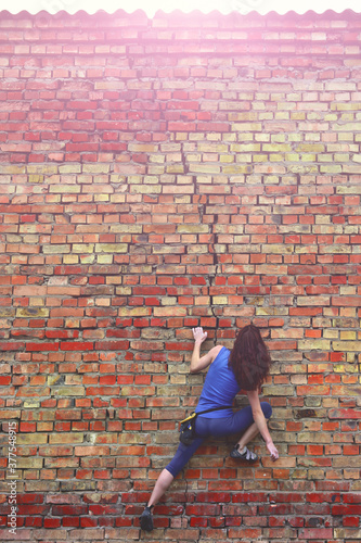 Free climbing on a brick wall. Woman climbing a brick wall. photo
