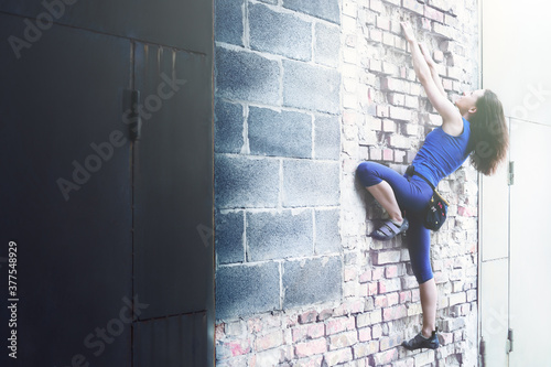 Free climbing on a brick wall. Woman climbing a brick wall. photo