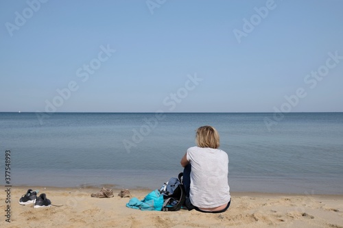Woman sitting on the sand at the beach of the Baltic Sea on a sunny summer day  Sobieszewska Island  Poland