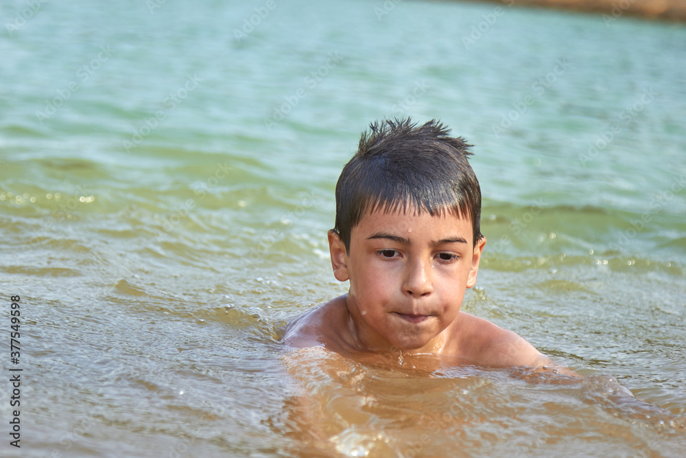 cute boy bathing in water in a lake in nature