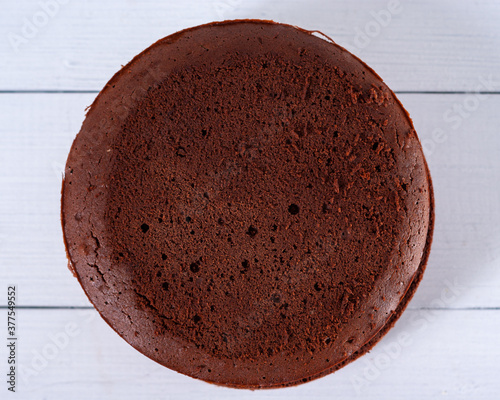 Obraz na plátne Round chocolate sponge cake on a light wooden background